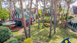 A residential area with a red house with a green roof, surrounded by trees and a well-maintained lawn. - Miss Loddin, Karl's Apartment (includes beach chair) - + Miss Loddin, Karl (Loddin)