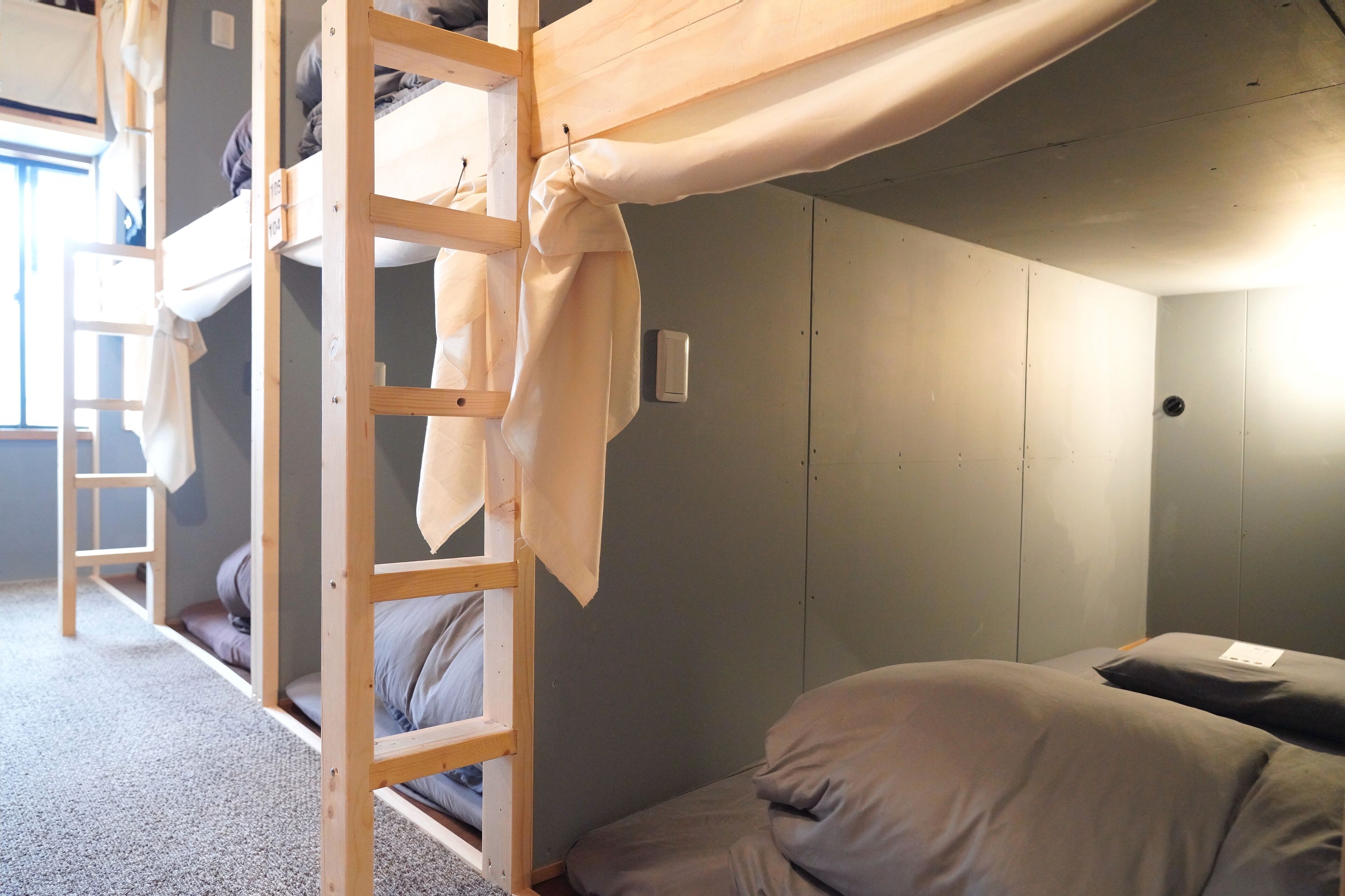 Habitación con literas, una escalera, una mesita pequeña y una cama individual.