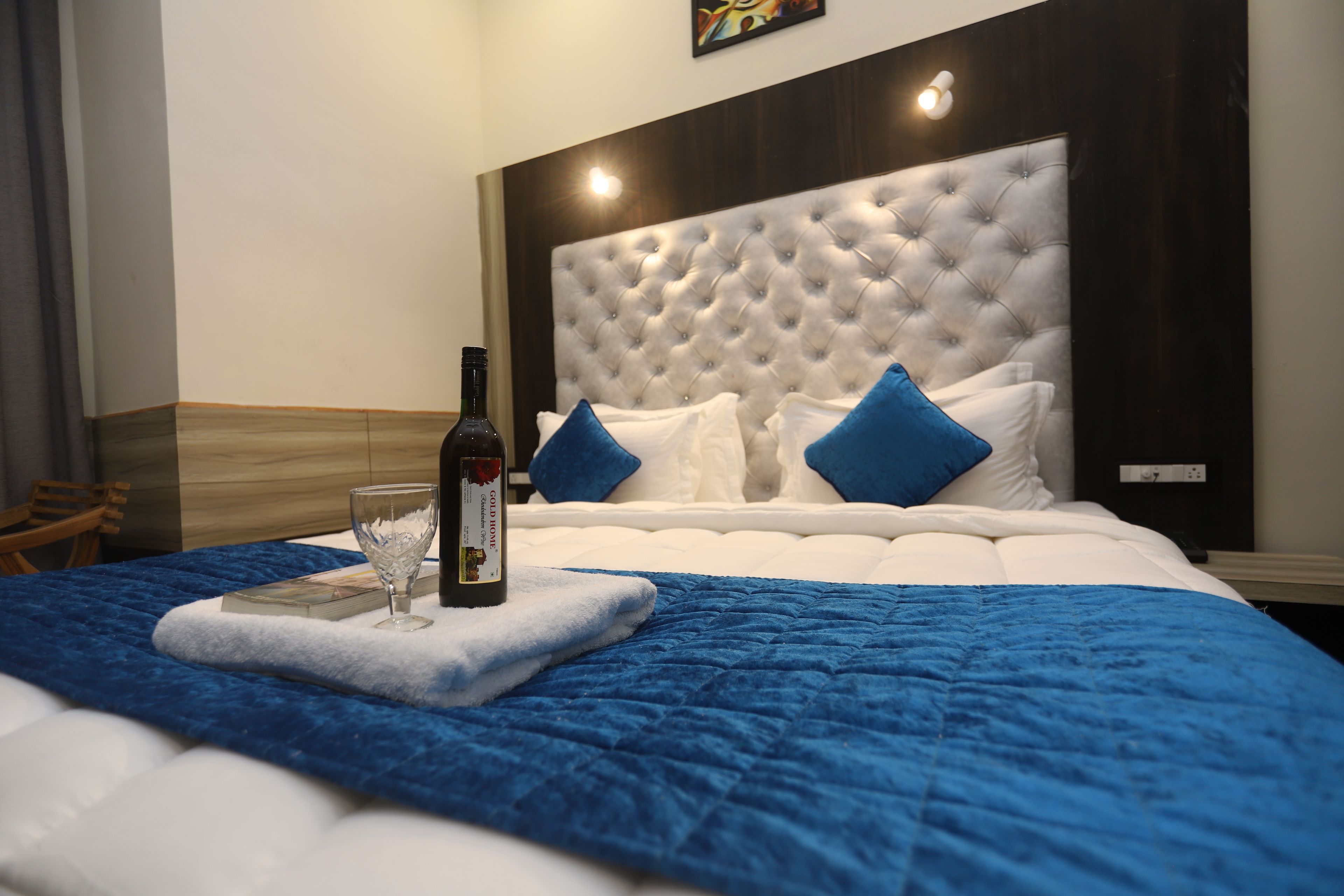 A hotel room with a large bed, a headboard, and a blue blanket.
