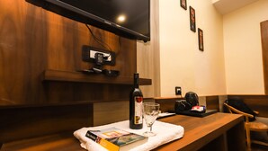 A wooden table with a book, a wine bottle, and a glass on a white cloth. - Hotel The Nest (Dharamshala)