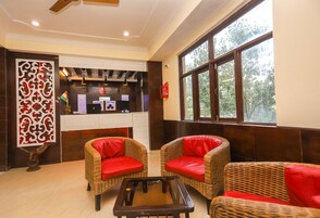 Un vestíbulo con muebles de mimbre, un mostrador de recepción y un ventanal grande.