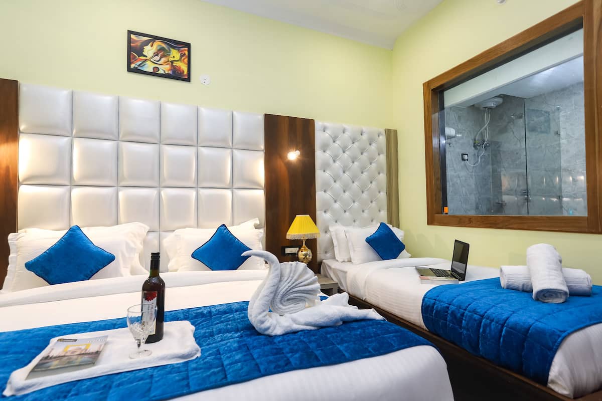 A hotel room with two beds, a large mirror, a shower, and a painting on the wall.