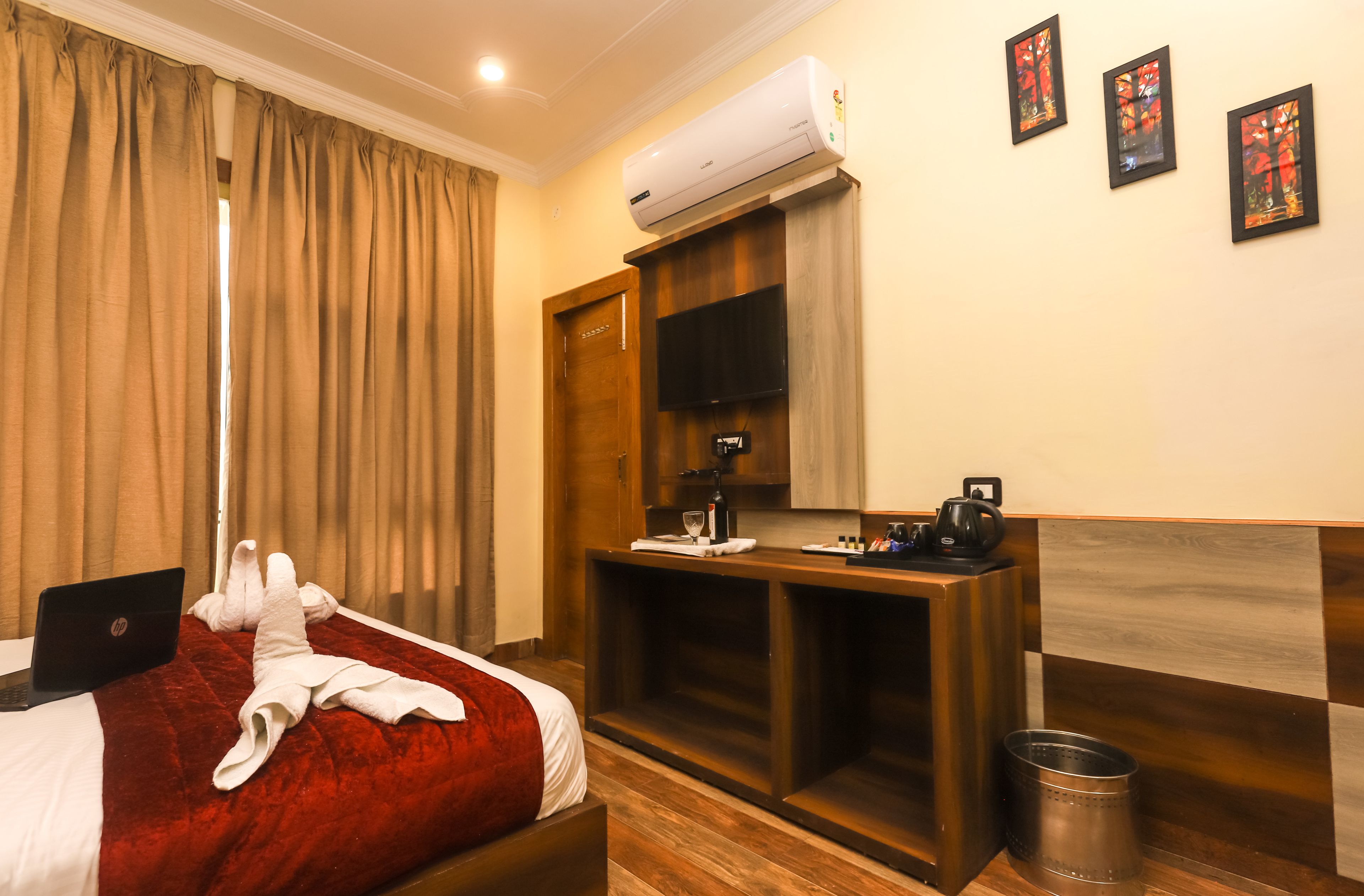 A hotel room with a bed, a desk, a TV, and an air conditioner.