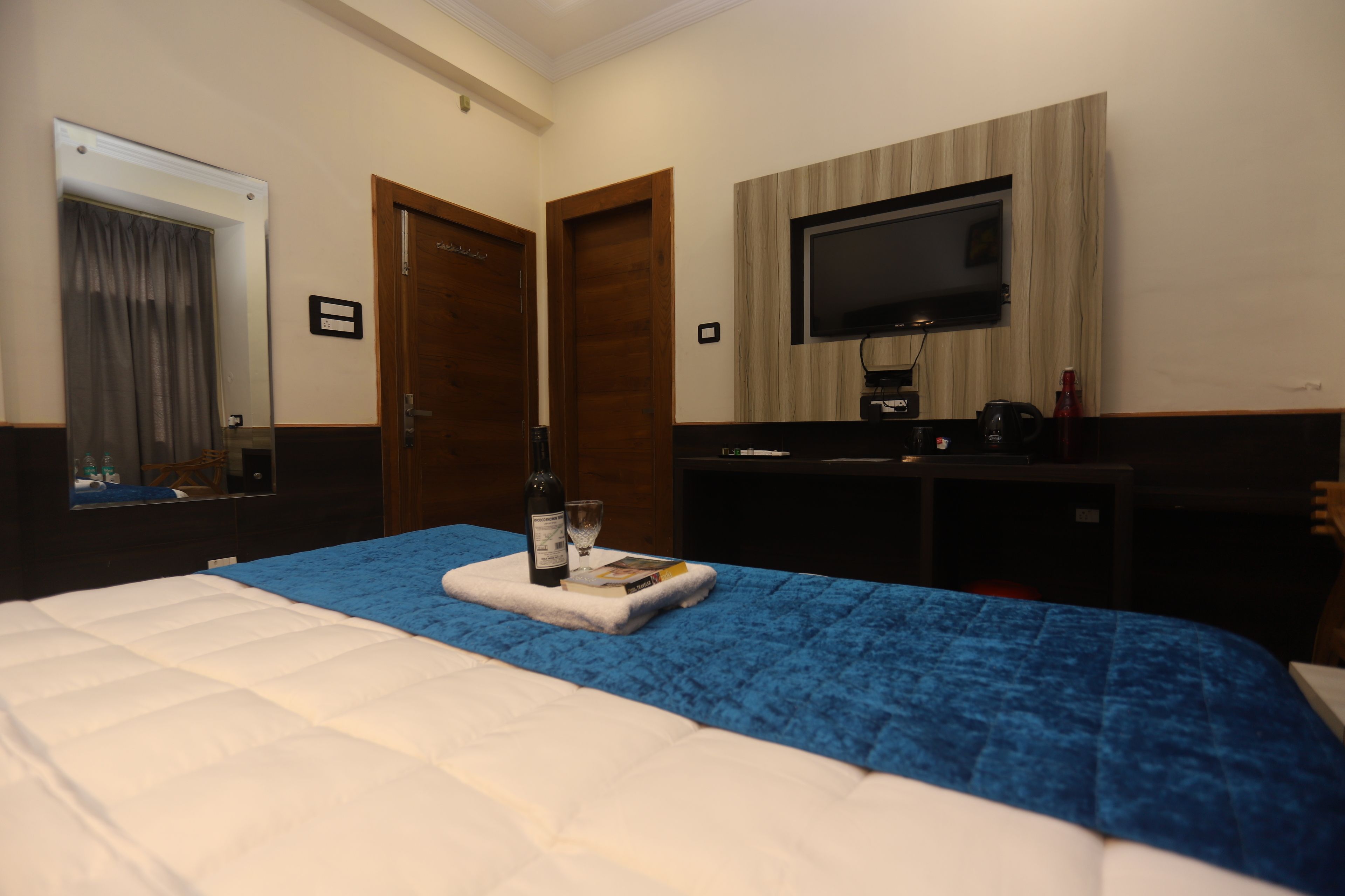 Ein Hotelzimmer mit einem Bett, einem an der Wand montierten Fernseher, einem Schreibtisch mit Computer und einer Tür.