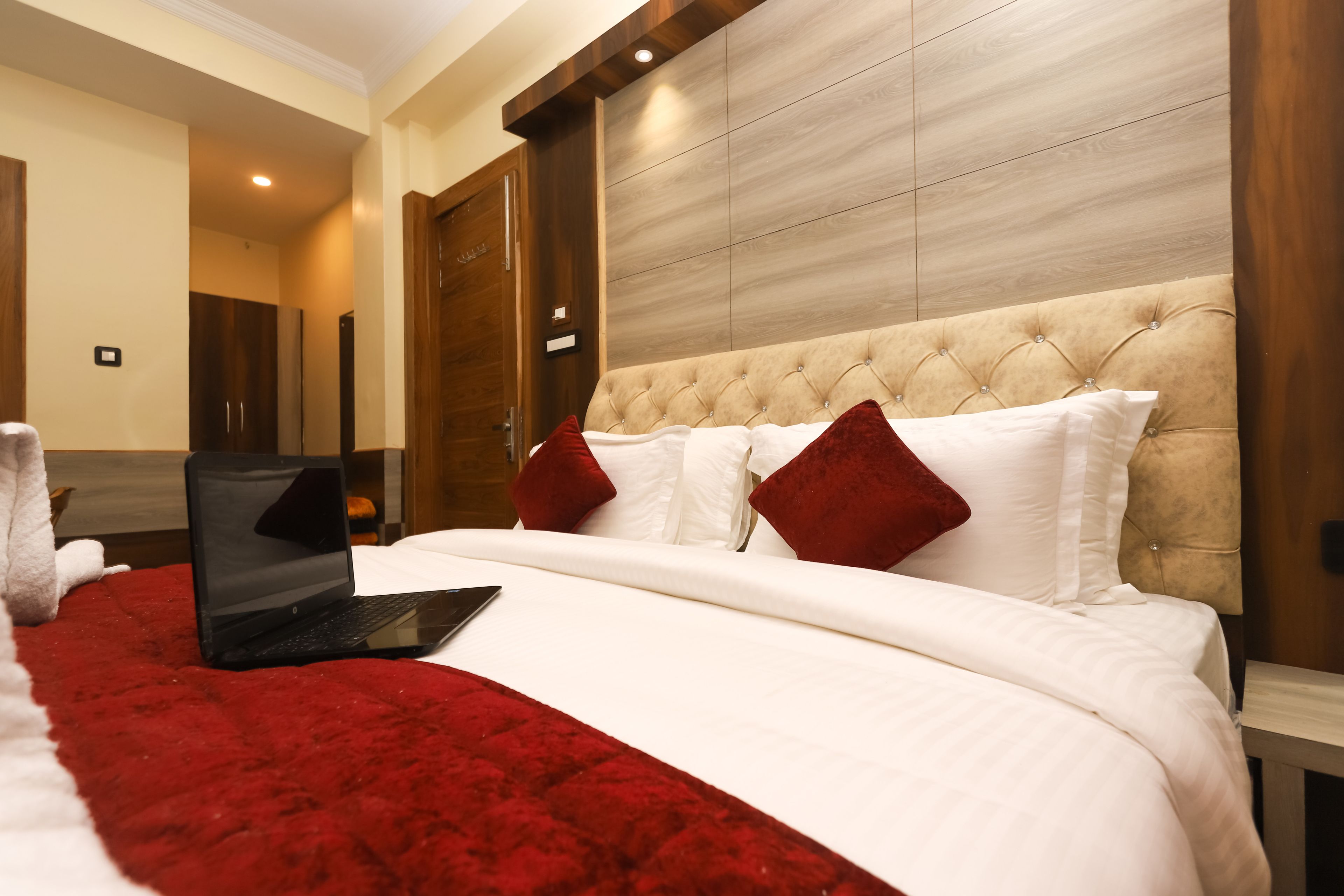 Ein Hotelzimmer mit einem großen Bett, einem Laptop auf dem Bett und einer roten Decke.