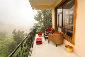 A balcony with wicker furniture, a red cushion, and a wicker basket. - Hotel The Nest (Dharamshala)