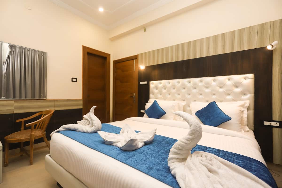 A hotel room with a large bed, a wooden chair, and a mirror.