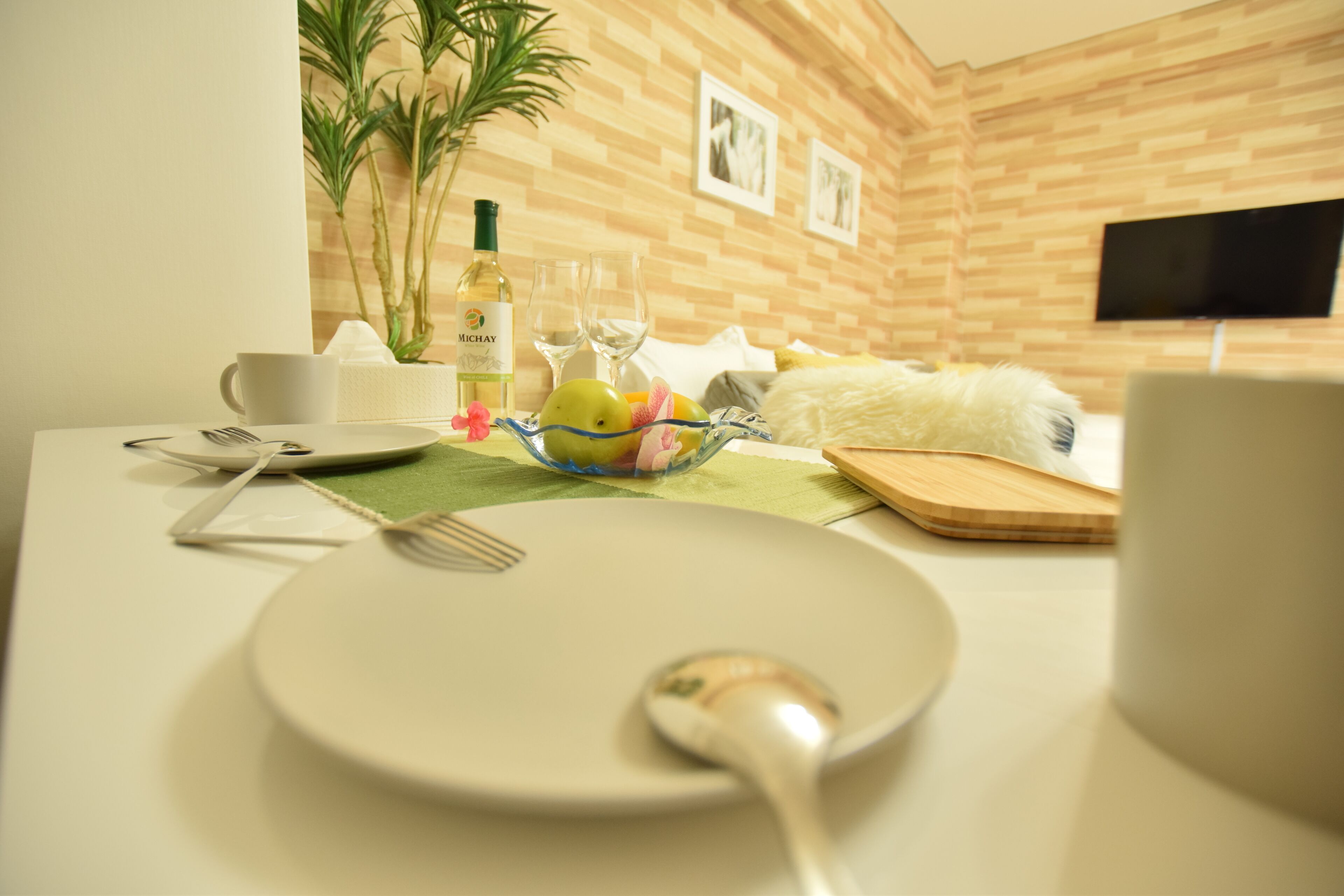 A breakfast setup with a plate, spoon, and a bowl of fruit on a table.