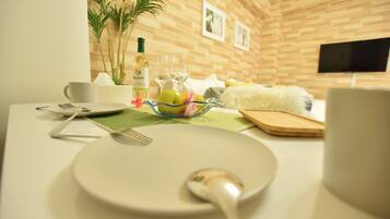 A breakfast setup with a plate, spoon, and a bowl of fruit on a table.