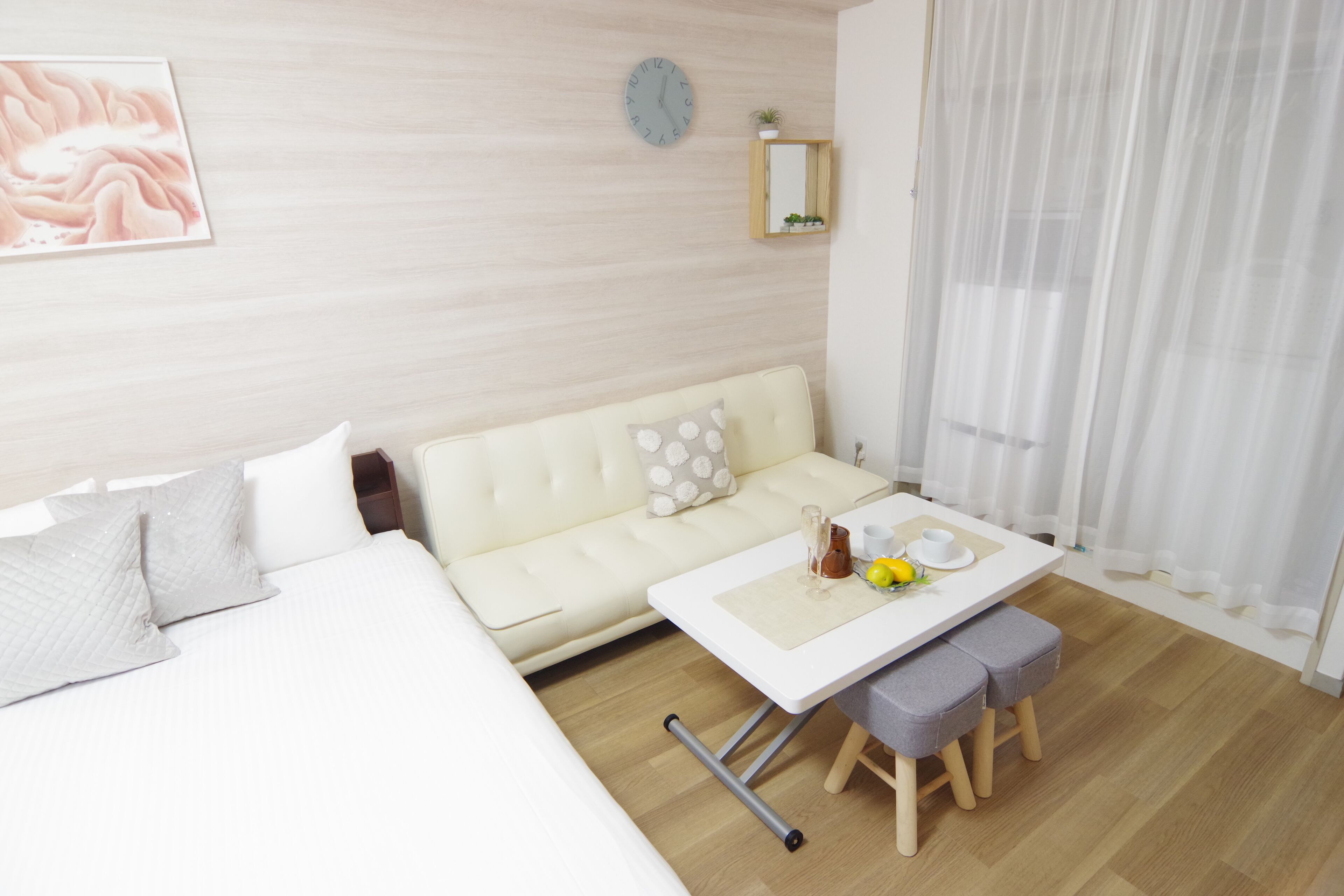 Et moderne hotelværelse med en seng, en sofa, et lille bord med en kop og citron, samt trægulv.