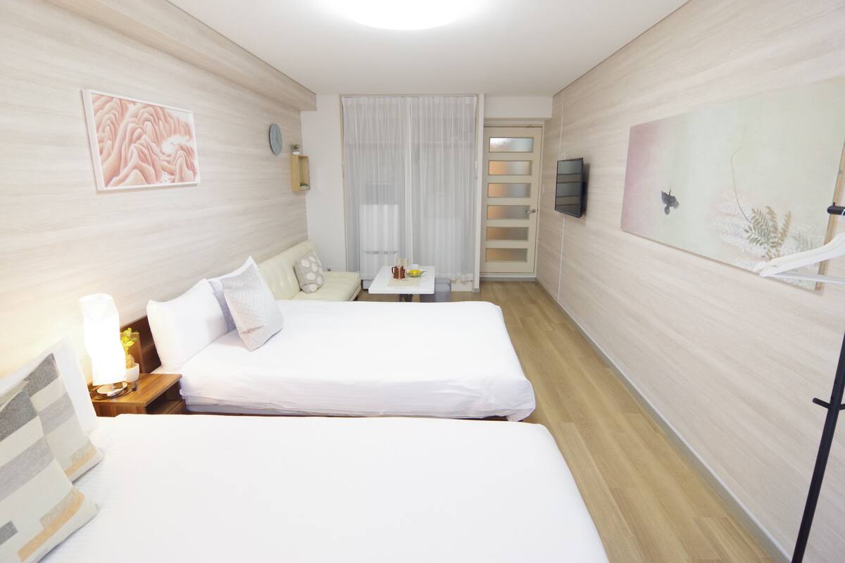 A hotel room with two beds, a small table with a plant, and artwork on the walls.