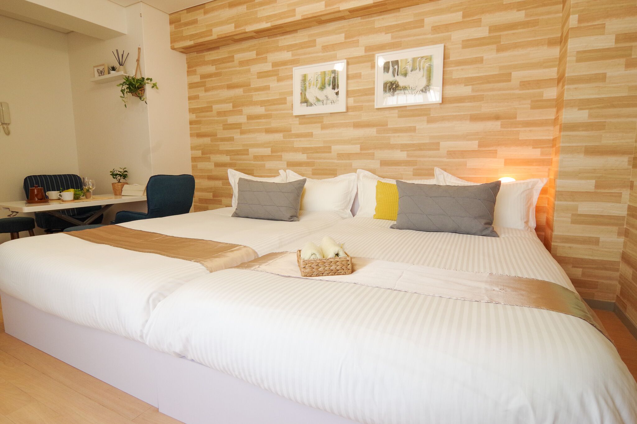 A neatly arranged hotel room with a large bed, a desk with a chair, and a small table with a plant.
