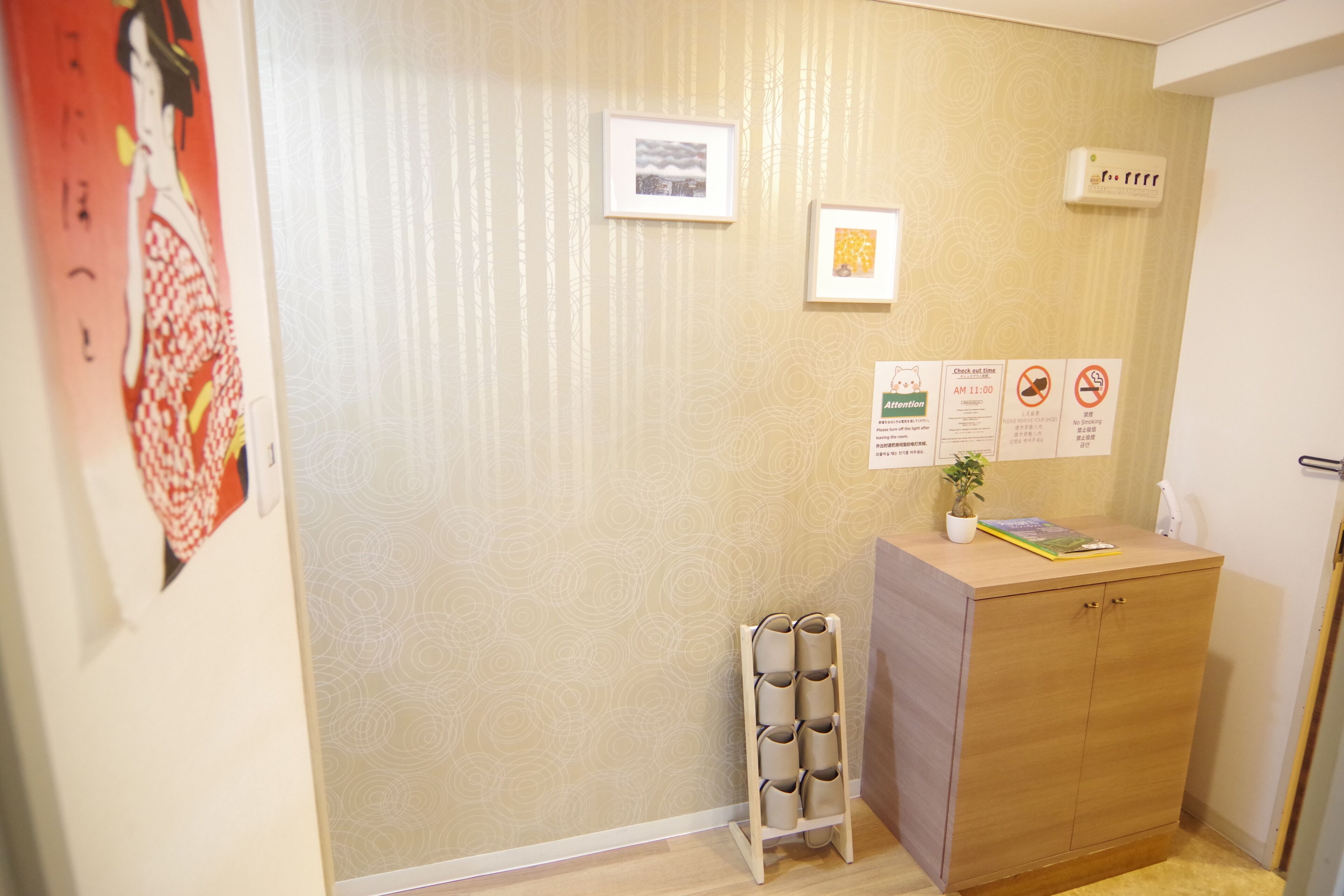 A room with a wooden cabinet, a small plant, and a wall with framed pictures and signs.