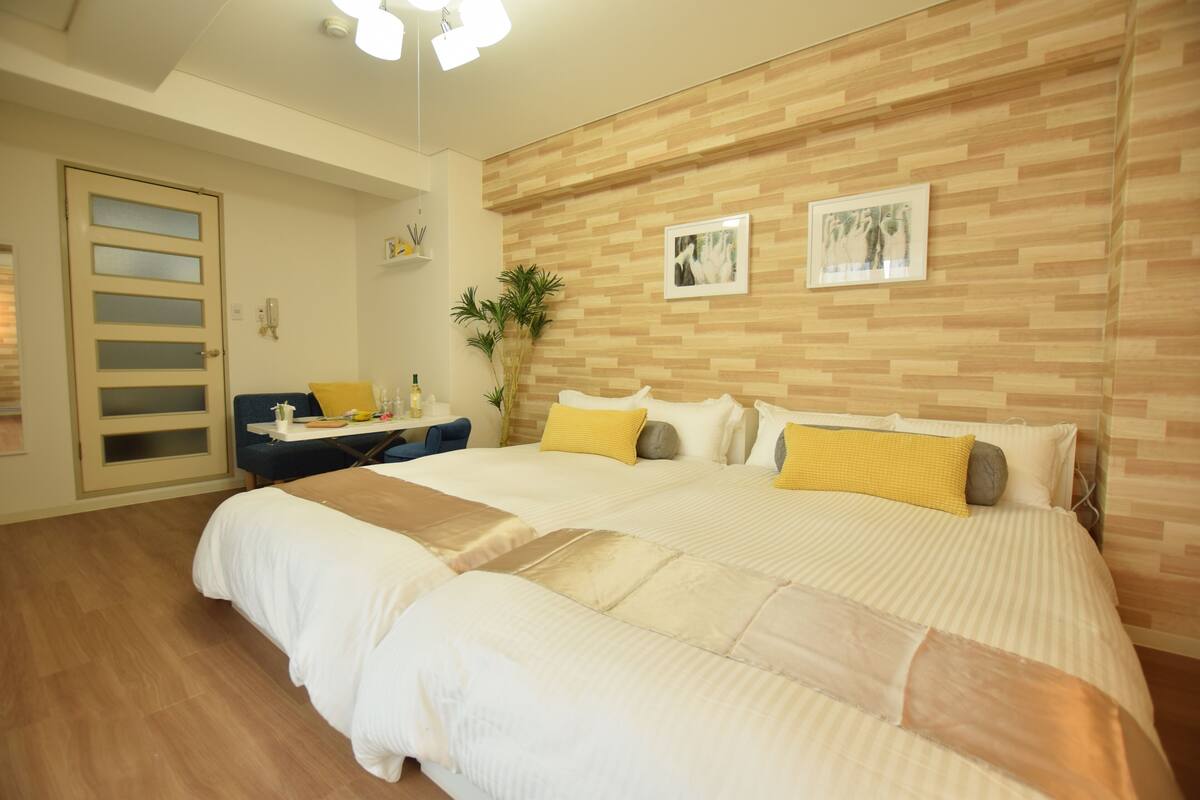 A spacious bedroom with a large bed, a desk with a chair, and a wooden wall with two framed pictures.