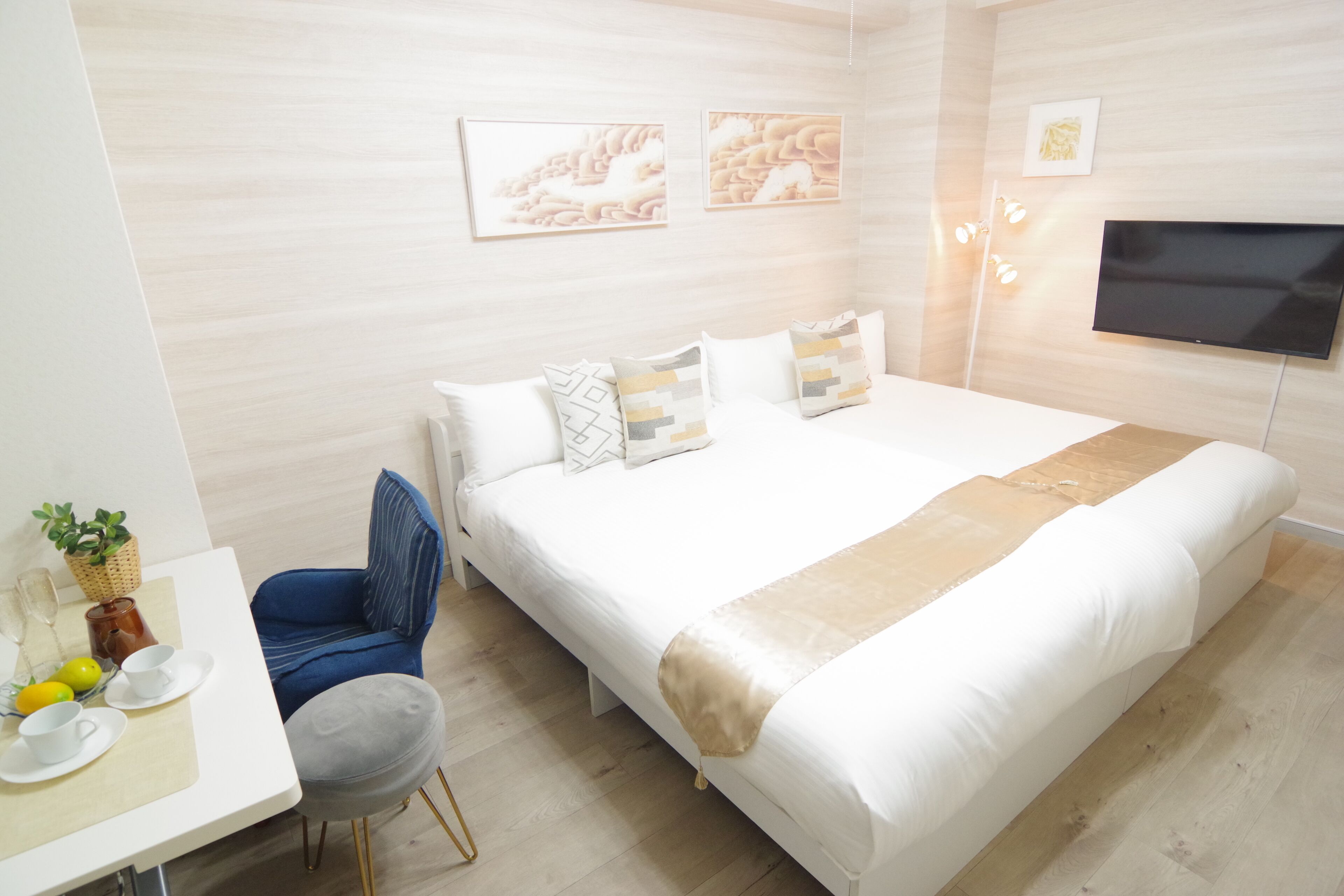 Ein modernes Schlafzimmer mit einem großen Bett, einem Schreibtisch mit Stuhl und einem an der Wand befestigten Fernseher.