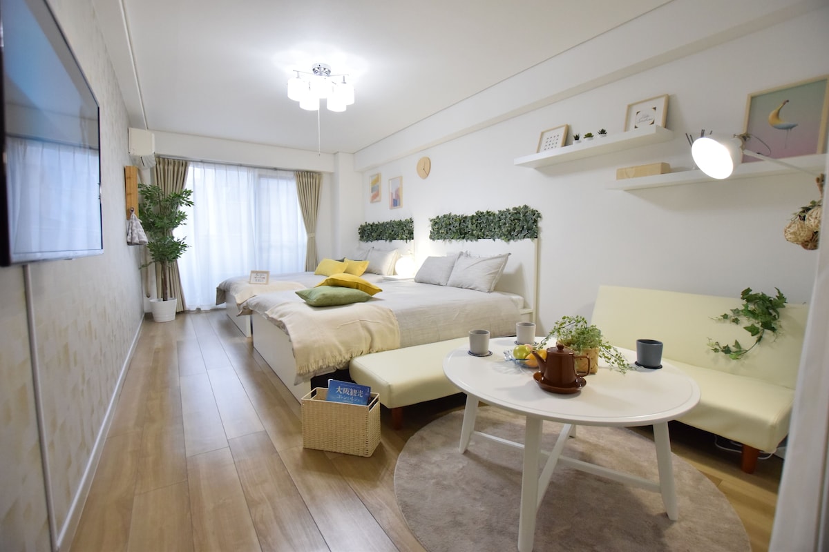 A modern, well-lit bedroom with a bed, bedside table, and a small seating area.