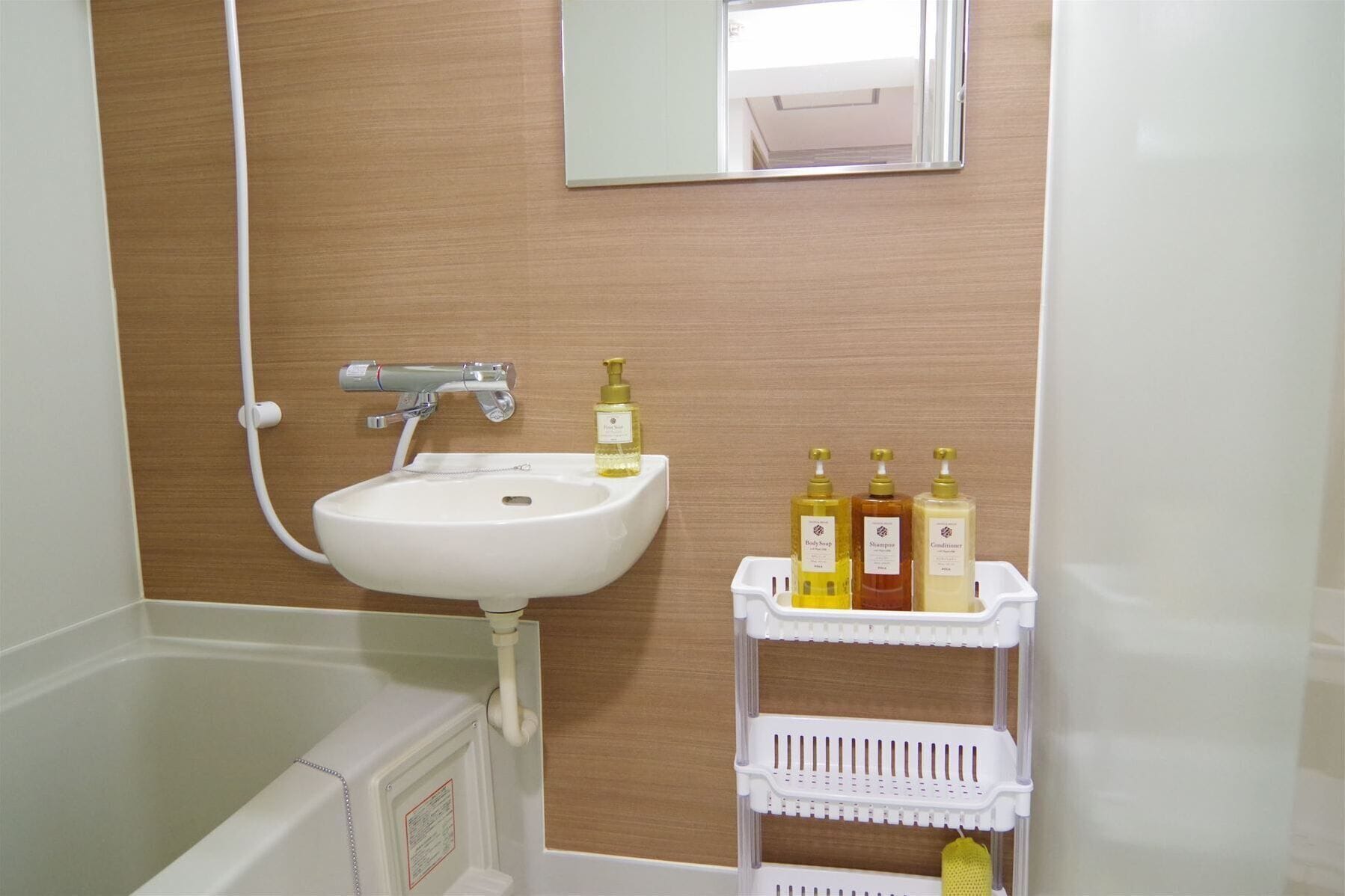 Un baño con un lavamanos blanco, un espejo y un estante con artículos de tocador.