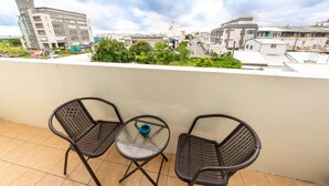 A balcony with two chairs and a small table, overlooking a cityscape with buildings and greenery. - Zheng Yi Homestay (Taitung)