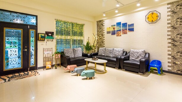 A modern living room with a sofa set, a coffee table, and decorative elements like a clock and artwork on the walls. - Zheng Yi Homestay (Taitung)