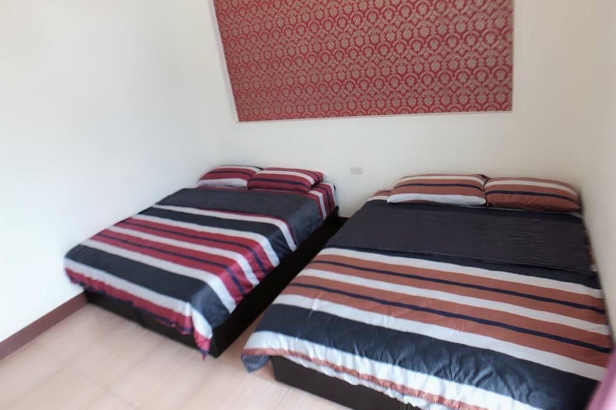 Una habitación con dos camas, cada una con ropa de cama a rayas y muchas almohadas.