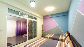 A bedroom with two beds, a sliding door to a balcony, and a geometric wall design. - Zheng Yi Homestay (Taitung)