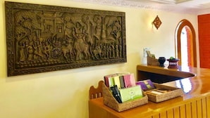 A reception area with a large decorative wall piece, a wooden reception desk, and wicker baskets containing items. - WEStay at Boutique House Bagan (Nyaung-U)