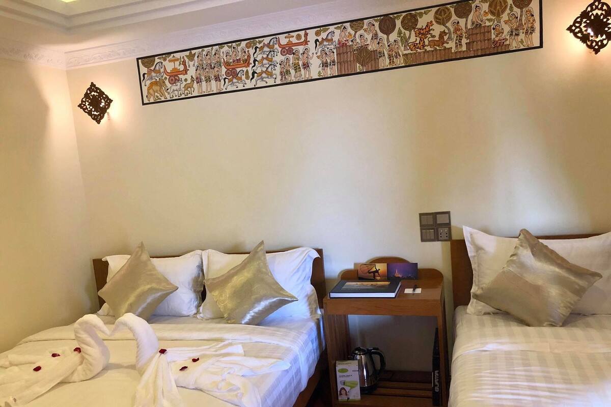 A hotel room with two beds, a wooden nightstand, and a decorative wall hanging.
