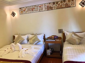 A hotel room with two beds, a wooden nightstand, and a decorative wall hanging. - WEStay at Boutique House Bagan (Nyaung-U)