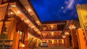 A multi-story hotel with a courtyard, featuring balconies and warm lighting. - WEStay at Boutique House Bagan (Nyaung-U)