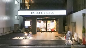 Der Eingang des Hotels Livemax mit modernem Design, darunter eine Glasfassade und ein Schild über den Türen.