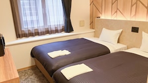 A hotel room with two beds, a wooden desk, a window with curtains, and a wall with a geometric pattern. - Hotel Livemax BUDGET Shimbashi (Tokyo)