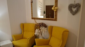 Two yellow armchairs, a white vase with flowers, a mirror with a gold frame, and a heart-shaped decoration on the wall. - Casa Isabella (Verona)