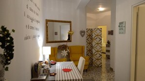 A dining area with a table, chairs, a mirror, and a wall with decorative elements. - Casa Isabella (Verona)