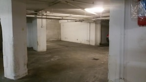 A spacious underground parking area with concrete floors and white walls. - Residenza Alla Piazzetta (Verona)