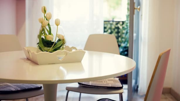 A round white table with a white decorative bowl containing a bouquet of white flowers. - Residenza Alla Piazzetta (Verona)