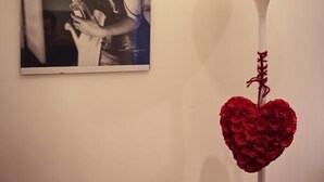A framed black and white photograph on a wall, a white floor lamp, and a heart-shaped decoration with red roses. - Residenza Alla Piazzetta (Verona)