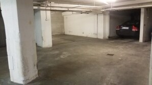 A parking garage with concrete floors and white walls, featuring several parking spaces and a car parked in one. - Residenza Alla Piazzetta (Verona)