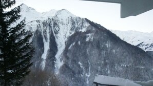 A snowy mountain landscape with a wooden bench and a snow-covered ground.