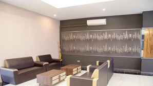 Eine moderne Hotelhalle mit einer Sofagruppe, einem Couchtisch und einem großen Wandbild.
