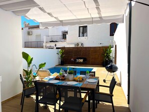 A covered outdoor dining area with a pool, wooden deck, and a view of a building with a balcony. - Nerja Paradise Rentals - Villa Topaz (Nerja)