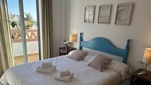 A neatly made bed with towels, a blue headboard, and two bedside lamps. - Nerja Paradise Rentals - Apartment Chimenea A1E (Nerja)
