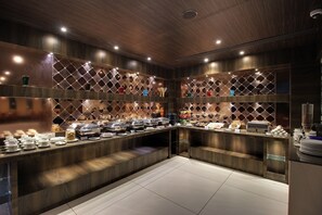 A buffet area with a wooden counter, multiple serving stations, and a tiled floor.
