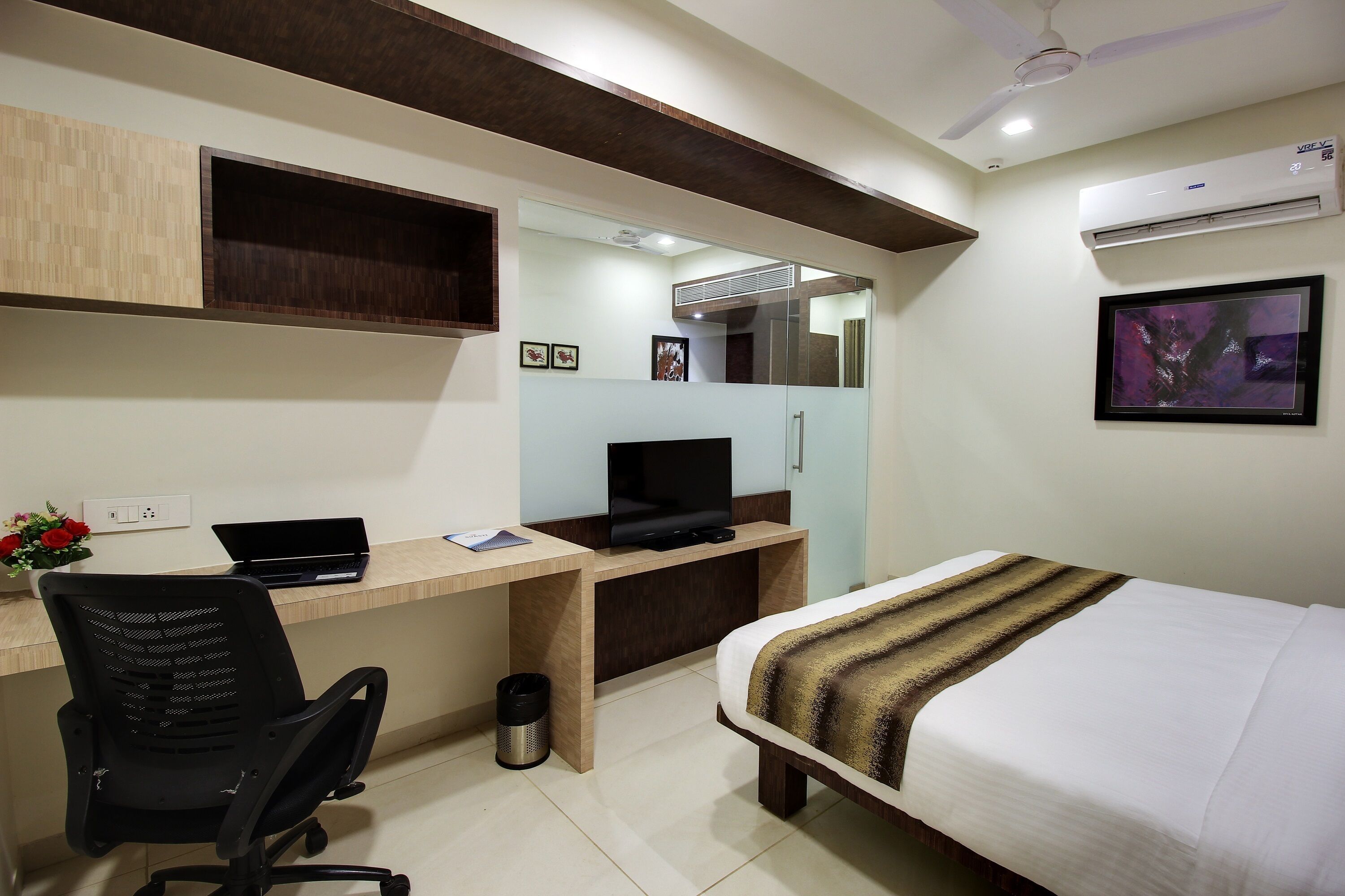 Une chambre d’hôtel équipée d’un lit, d’un bureau, d’une chaise, d’une télévision et d’un appareil de climatisation.