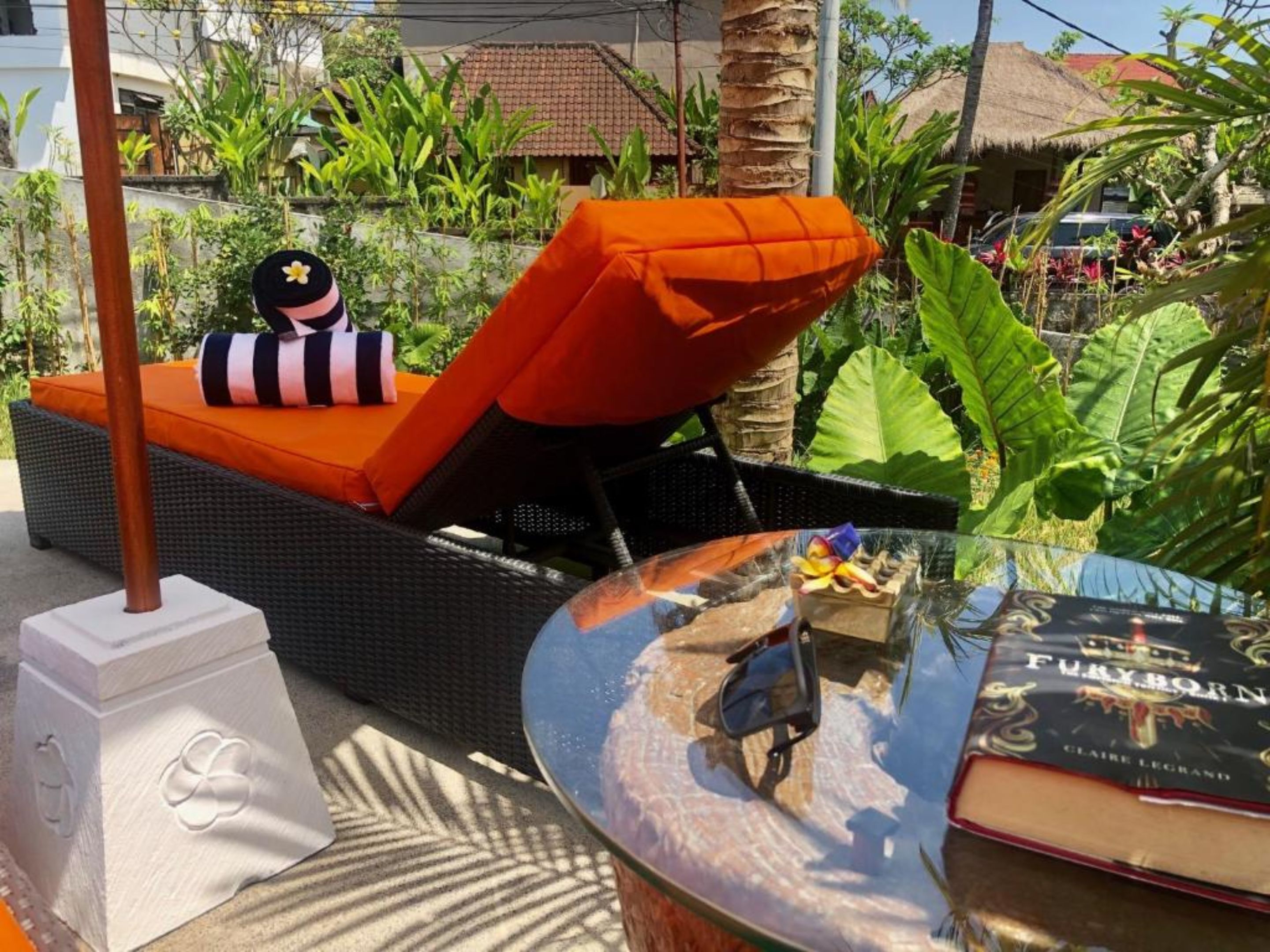 Een rieten lounge stoel met een oranje kussen en een zwart kussen met een sterrenpatroon.
