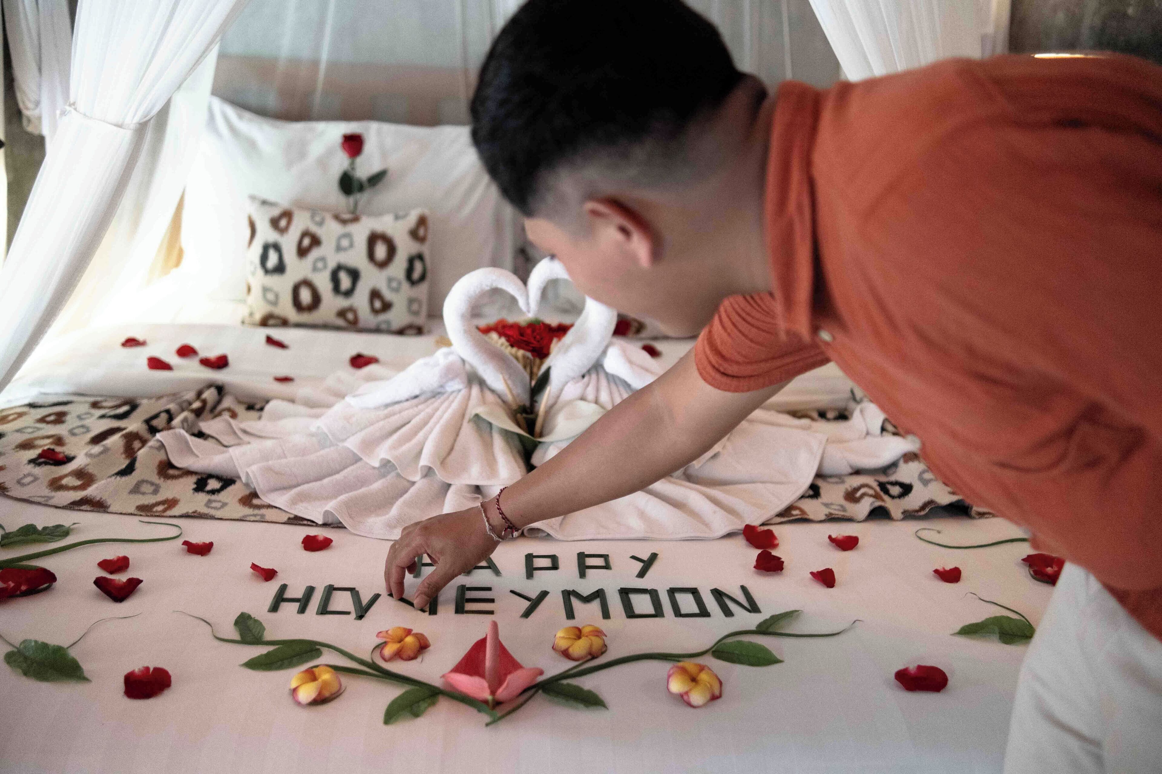 A bed with a message "Happy Honeymoon" and decorative flowers.