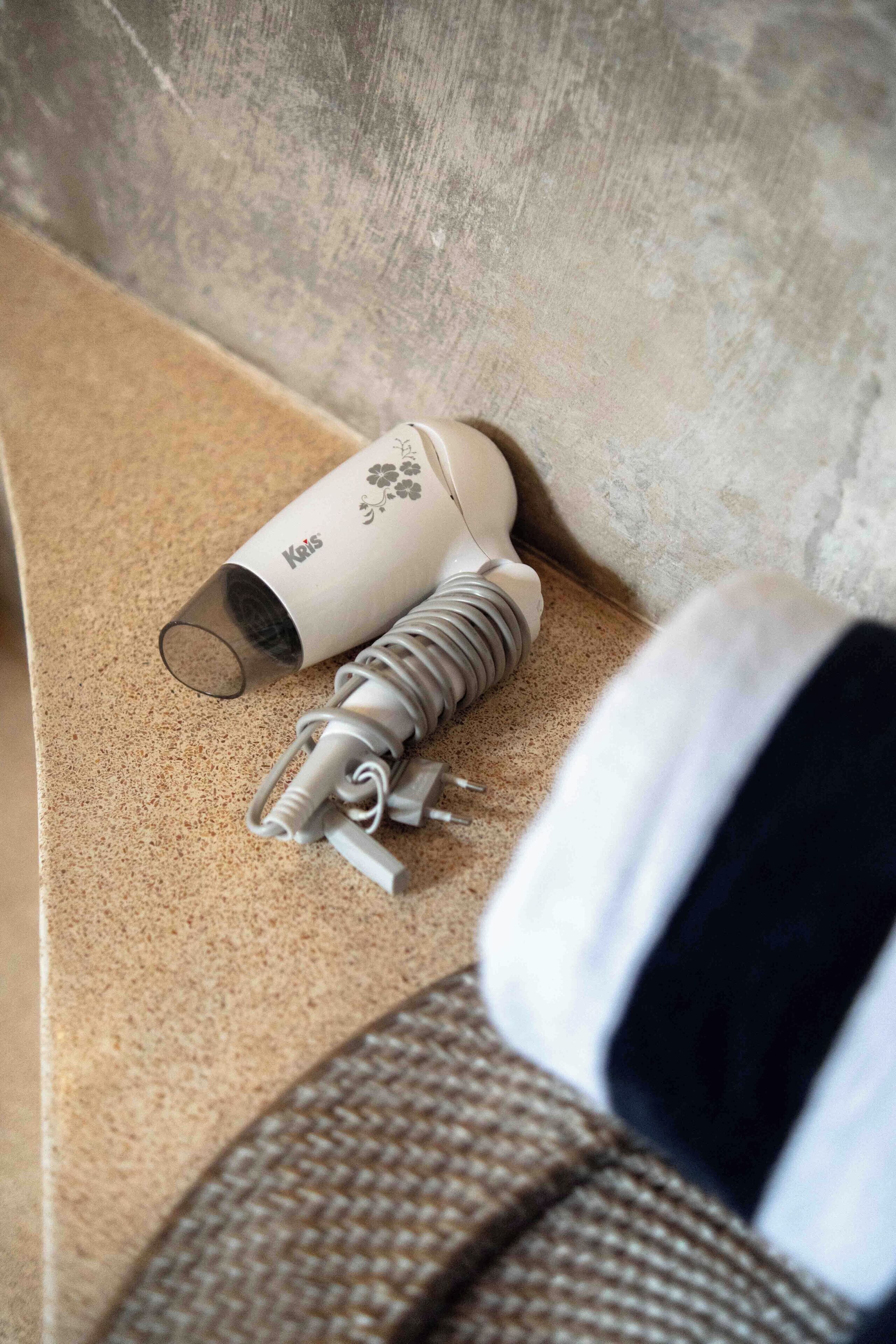 A hairdryer and its accessories on a textured surface, possibly a bathroom counter.