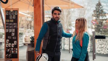 A man holding a helmet, standing next to a woman in a teal jacket.