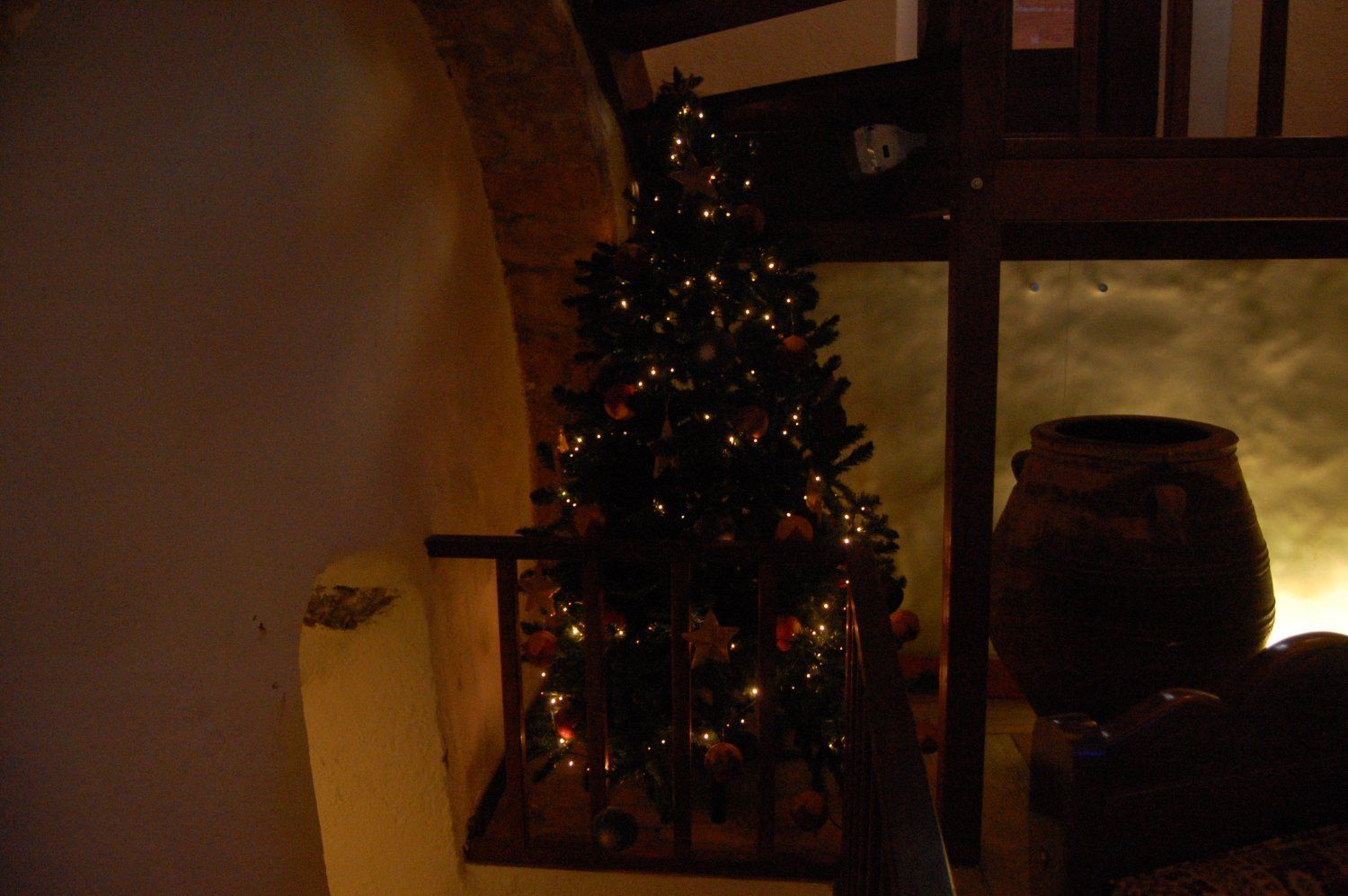 Um quarto escuro com uma árvore de Natal e uma panela grande.