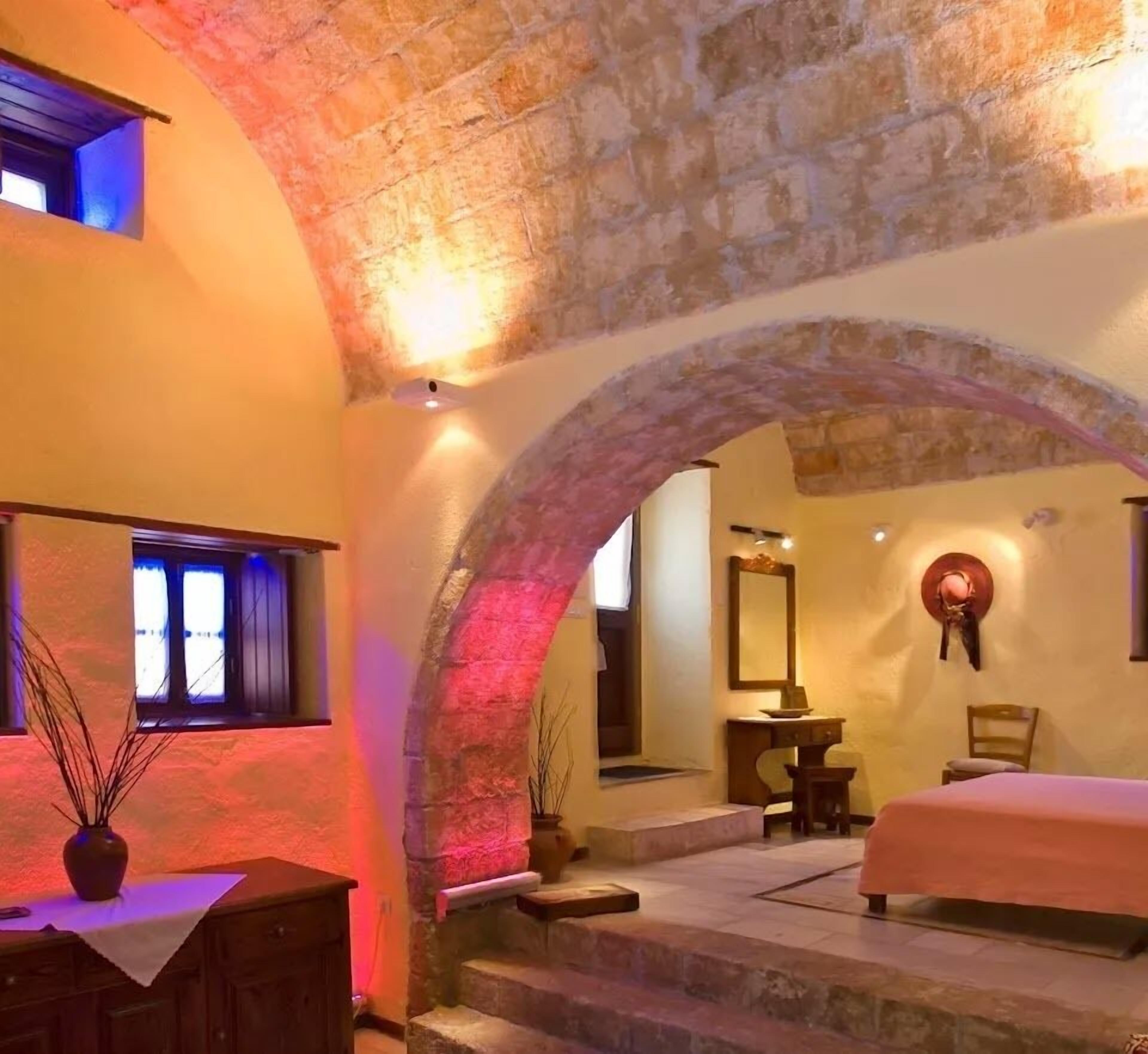 Ein Schlafzimmer mit einem Steingewölbe, einem Bett, einem Schreibtisch und einem Stuhl.