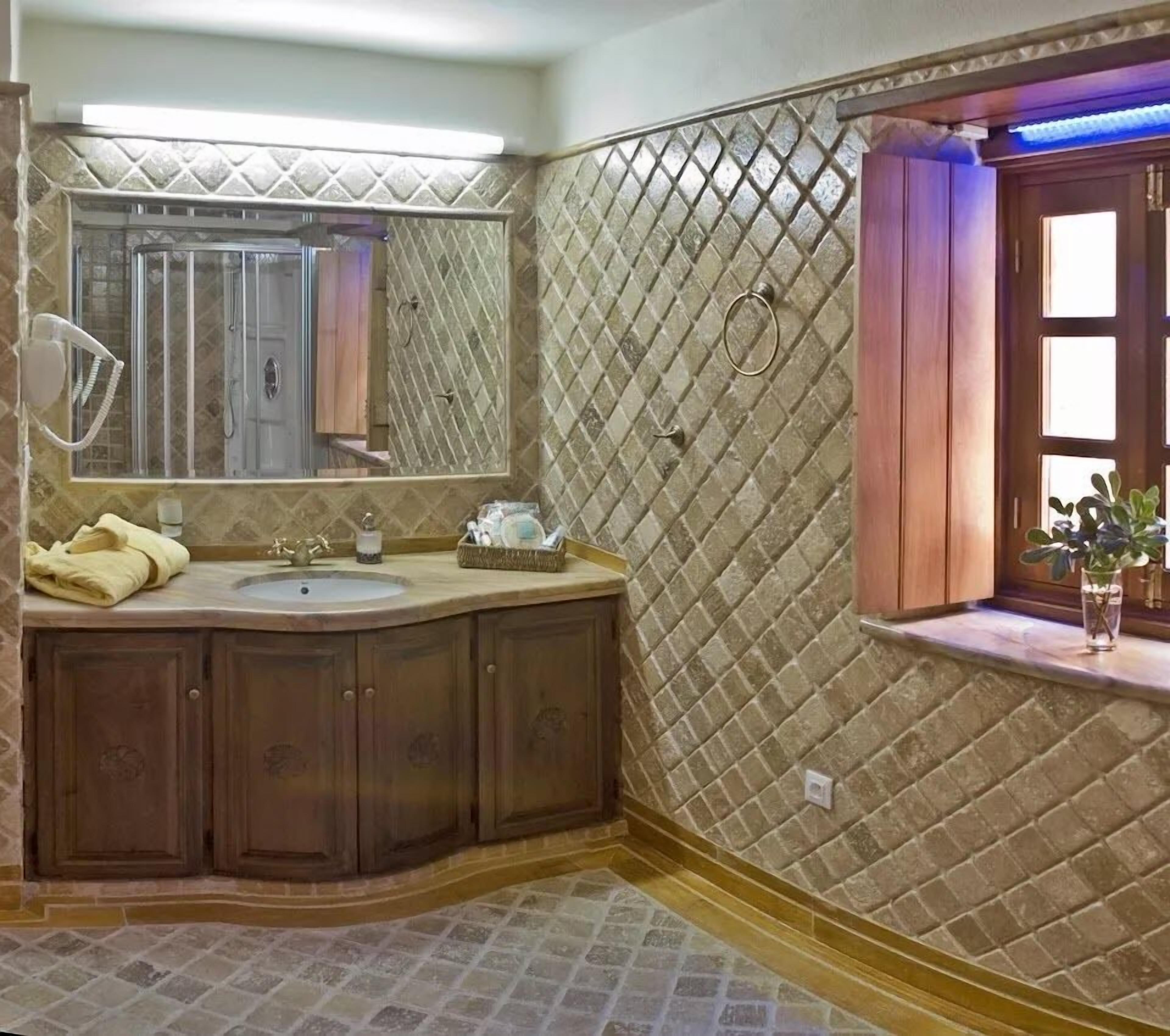 Un baño con un espejo grande, un lavabo y un mueble de tocador con armarios. Hay una ventana con vistas al exterior.